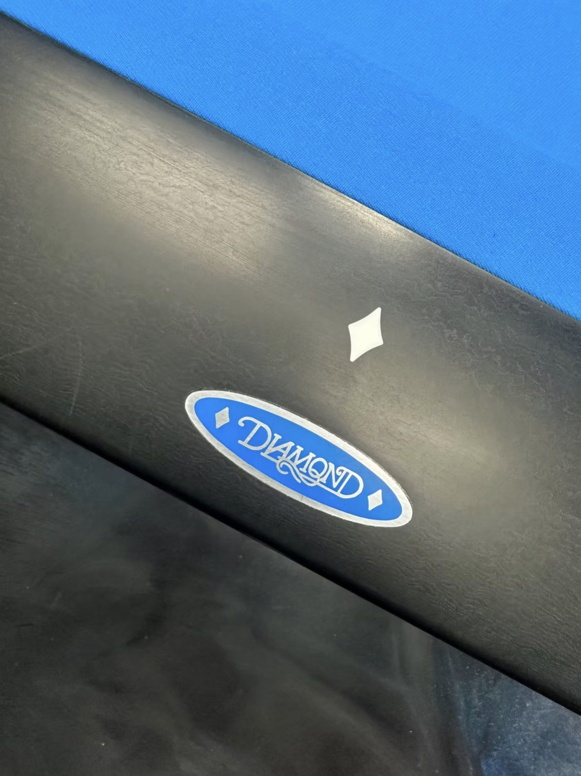 The Diamond badge on the black rail of a Dynasty table